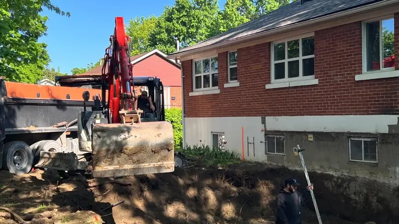 Excavating the foundation of a home addition behind a brick bungalow