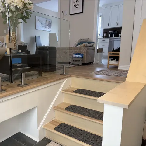 Garde-corps en verre trempé sur poteaux en acier inoxydable et escalier en érable dans un salon