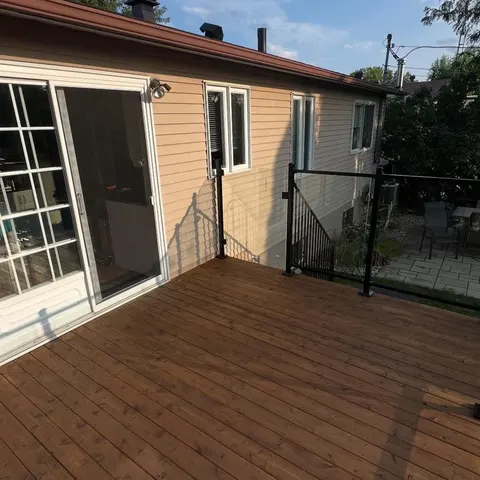 Large wood deck with railing in front of a patio door