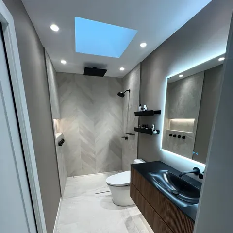 Walk-in shower with herringbone tile, skylight and black fixtures — bathroom renovation by Construction 3 Lacs