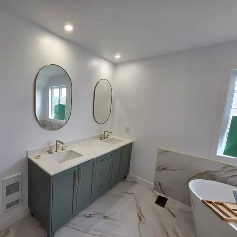 Vanité double vert sauge avec comptoir de quartz blanc, robinetterie et poignées en laiton et miroirs ovales