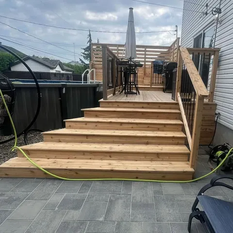 Wide cedar staircase leading to a deck with privacy screen