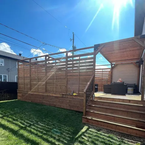 Terrasse en cèdre teint avec pergola, écran d’intimité à lattes horizontales et escalier large
